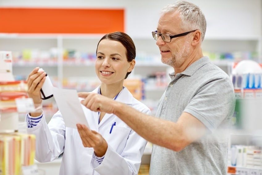 Farmaceut och kund granskar tillsammans ett läkemedelsrecept på apotek